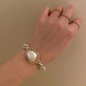 Elegant beaded pearl bracelet with gold metal frame and micro-rhinestones on a model's wrist