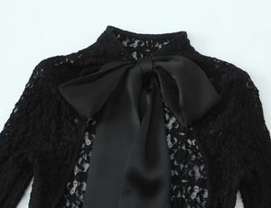 Detailed view of black lace bodice featuring a large satin bow and intricate mesh texture