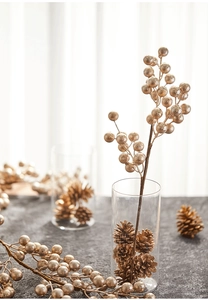 Champagne gold faux berry branches with pine cones in a glass vase for festive home decor
