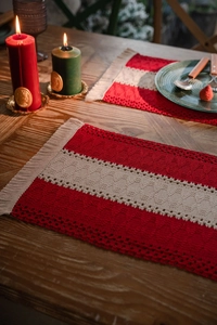 Close-up of red and white woven cotton Christmas placemat with tassels on wooden table