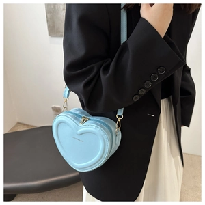 Detail of light blue heart-shaped crossbody bag with stylish fashion text and gold zipper
