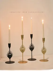 Detailed view of peacock feather hollow iron candle holders in black and gold finishes