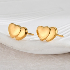 Macro shot of minimalist gold double heart earrings with polished metallic luster