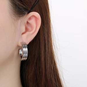 Close-up of a silver-toned triple C-shaped hoop earring on a model with a polished finish