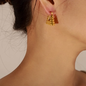 Gold plated geometric triangle handbag style earrings with stud texture on a model