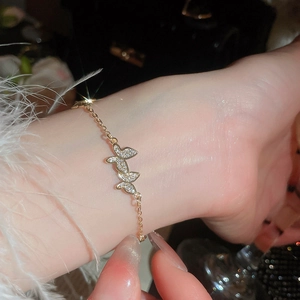 Macro shot of gold butterfly bracelet with shimmering zircon pavé and delicate link chain