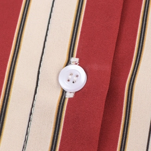 Gros plan sur un tissu rayé rouge et beige avec un détail de bouton blanc à quatre trous