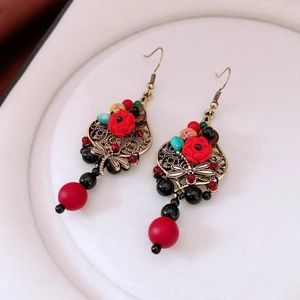 Detail of vintage dragonfly earrings with red resin beads and golden filigree design