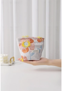 Detail of floral makeup bag with metal zipper and flower charm in hand
