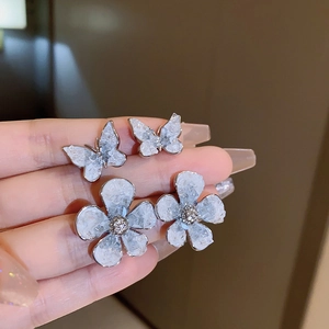 Detail of gradient crystal flower and butterfly stud earrings with ice-cracked texture