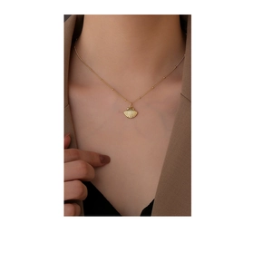 Close-up of golden shell pendant necklace with bead chain on model neck