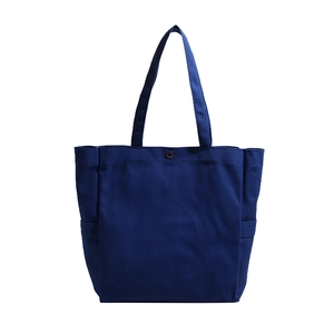 Navy blue canvas tote bag with side pocket and metal button closure in minimalist style
