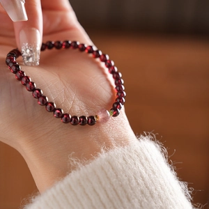 Macro detail of garnet beads bracelet with pink crystal accent and golden metal spacers