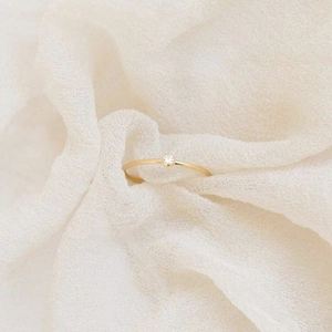 Primer plano de un anillo de oro fino minimalista con un solo diamante redondo brillante