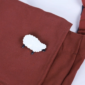Fashionable white acrylic sheep brooch pinned on a brown canvas bag flap as a cute accessory