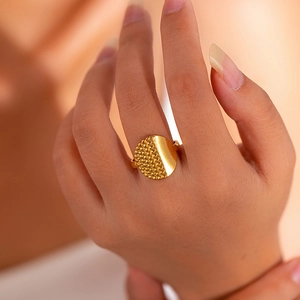 Close-up of golden titanium steel ring featuring smooth and beaded textures on a finger