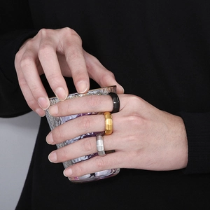 Close-up of three minimalist matte titanium rings in black, gold, and silver finishes