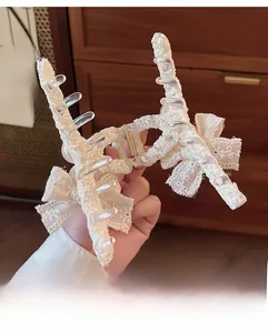 Détail de la pince à cheveux en dentelle blanche avec nœuds et perles élégantes