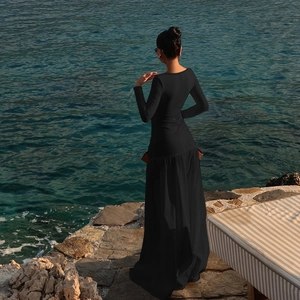 Long sleeve black maxi dress with hollow out details shown on beach stones