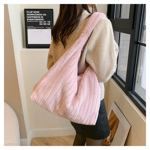 Detail of soft pink faux fur shoulder bag worn by model in a minimalist indoor setting