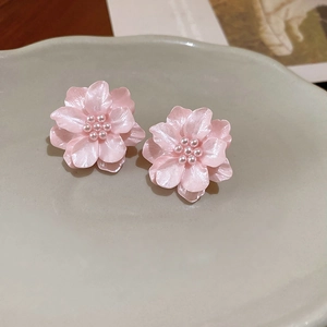 Dettaglio di orecchini a lobo a fiore rosa con centro di perle su vassoio