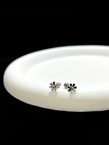 Detailed view of silver polished flower stud earrings with secure screw-on ball backings