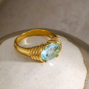 Macro detail of 18k gold stainless steel ring with oval blue gemstone and ribbed texture