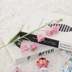 Detailed view of handmade pink crochet lily of the valley flowers on decorative books