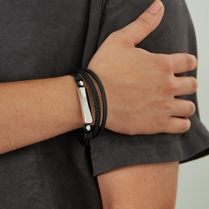 Detailed view of men's multilayered black leather bracelet with silver metal accent