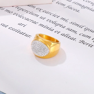 Macro shot of gold-plated wide band ring featuring a sparkling pavé crystal oval setting