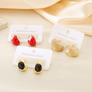 Three pairs of elegant stainless steel earrings with gemstones on a silk background
