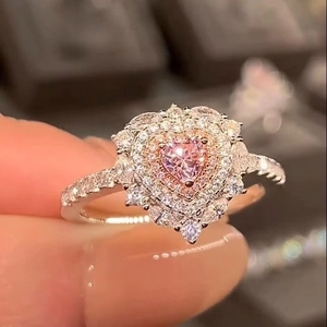 Primo piano dell'anello con diamante a cuore rosa e cristalli scintillanti sul metallo