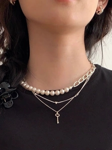 Close-up of layered S925 silver necklace with pearls and a heart key pendant