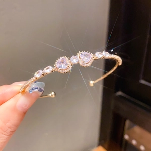 Detailed close-up of a sparkling gold heart-shaped zircon bangle with brilliant crystal stones