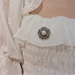 Luxuriöse Barock-Kamelien-Brosche mit dunklen Kristallen und Perle auf einer weißen Bluse