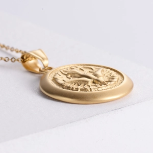 Macro view of a gold-plated stainless steel coin pendant with a dove of peace relief