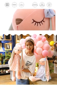 Close-up of pink plush bunny doll with floral dress and cute embroidered facial details