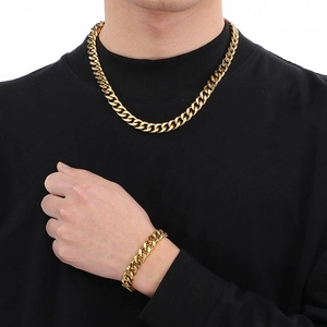 Gros plan d'un ensemble collier et bracelet maille gourmette dorée porté par un mannequin