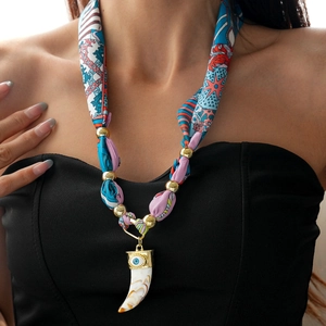 Detail of silk scarf necklace with golden beads and ivory-style elephant eye pendant