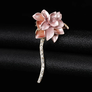 Macro detail of a pink enamel lotus brooch featuring sparkling rhinestone stems on leather