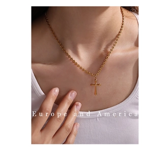 Detailed view of an 18K gold plated cross pendant necklace on a heart link chain