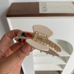 Close-up of beige tulip hair claw clip with red patterns and metal spring mechanism