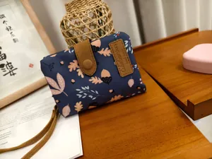 Close-up of blue fabric wallet featuring maple leaf prints and leather snap closure