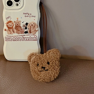 Detail of off-white wavy phone case with brown plush bear charm and motivational text
