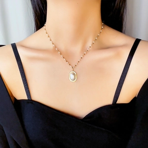 Elegant gold titanium steel necklace featuring oval pearl pendant on a beaded chain