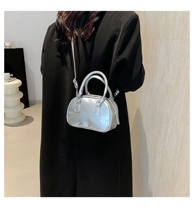 Silver metallic mini handbag with dual handles and slim shoulder strap on black coat