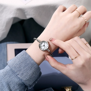 Detailed close-up of a silver-toned bangle watch with white dial and quartz movement