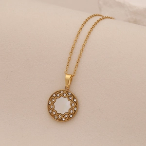 Macro shot of gold heart pendant necklace with shimmering crystals and white shell inlay
