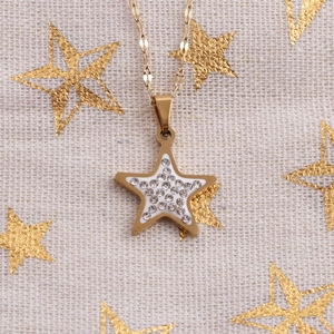 Close-up of golden star necklace with crystal inlay on a starry fabric background