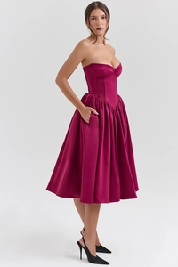 Dettaglio dell'abito midi in raso fucsia con corpetto a corsetto e gonna a pieghe con tasche
